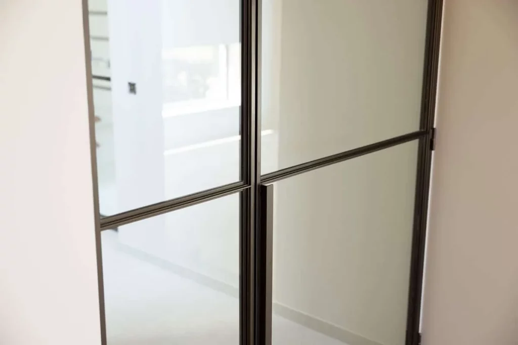 Detail van de slanke stalen profielen met glaslatten in koper- en bronskleur in plaats van mastiek.