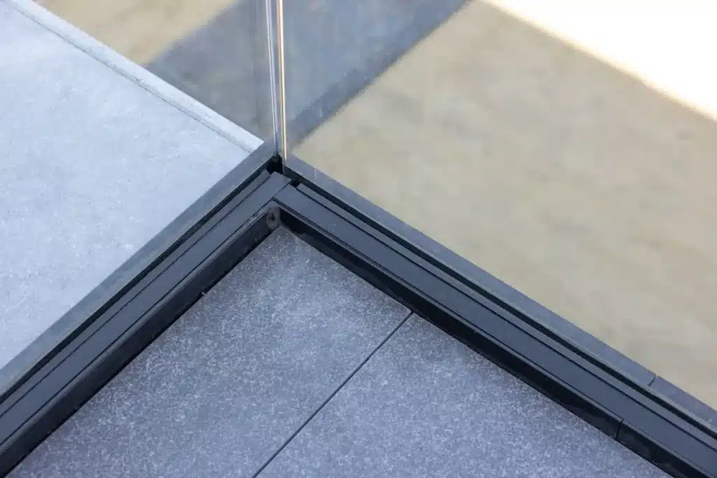 Detail van de hoekverbinding van het zwarte profiel van de glazen balustrade op het terras.