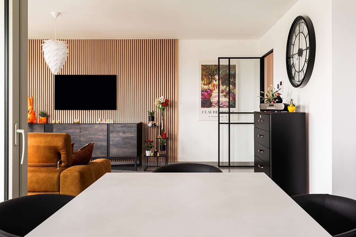 Leefruimte van een appartement met eettafel en zithoek, met achteraan de stalen binnendeur naar de hal.