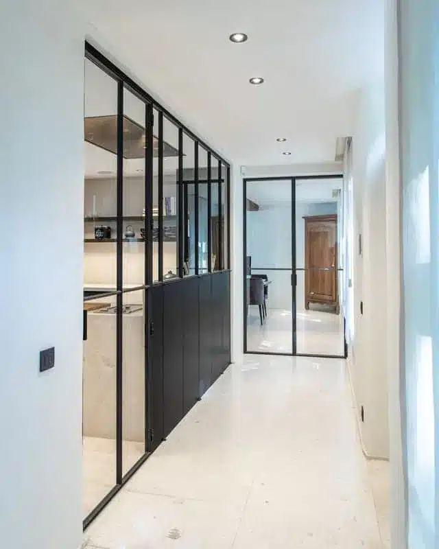 Gang met de stalen keukenwand aan de linkerzijde en een stalen dubbele deur naar de eetkamer achteraan.