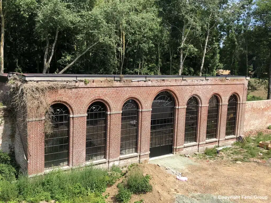 Bakstenen gevel van de orangerie met een reeks nieuwe XL boogramen met roedeverdeling tussen de pilasters.