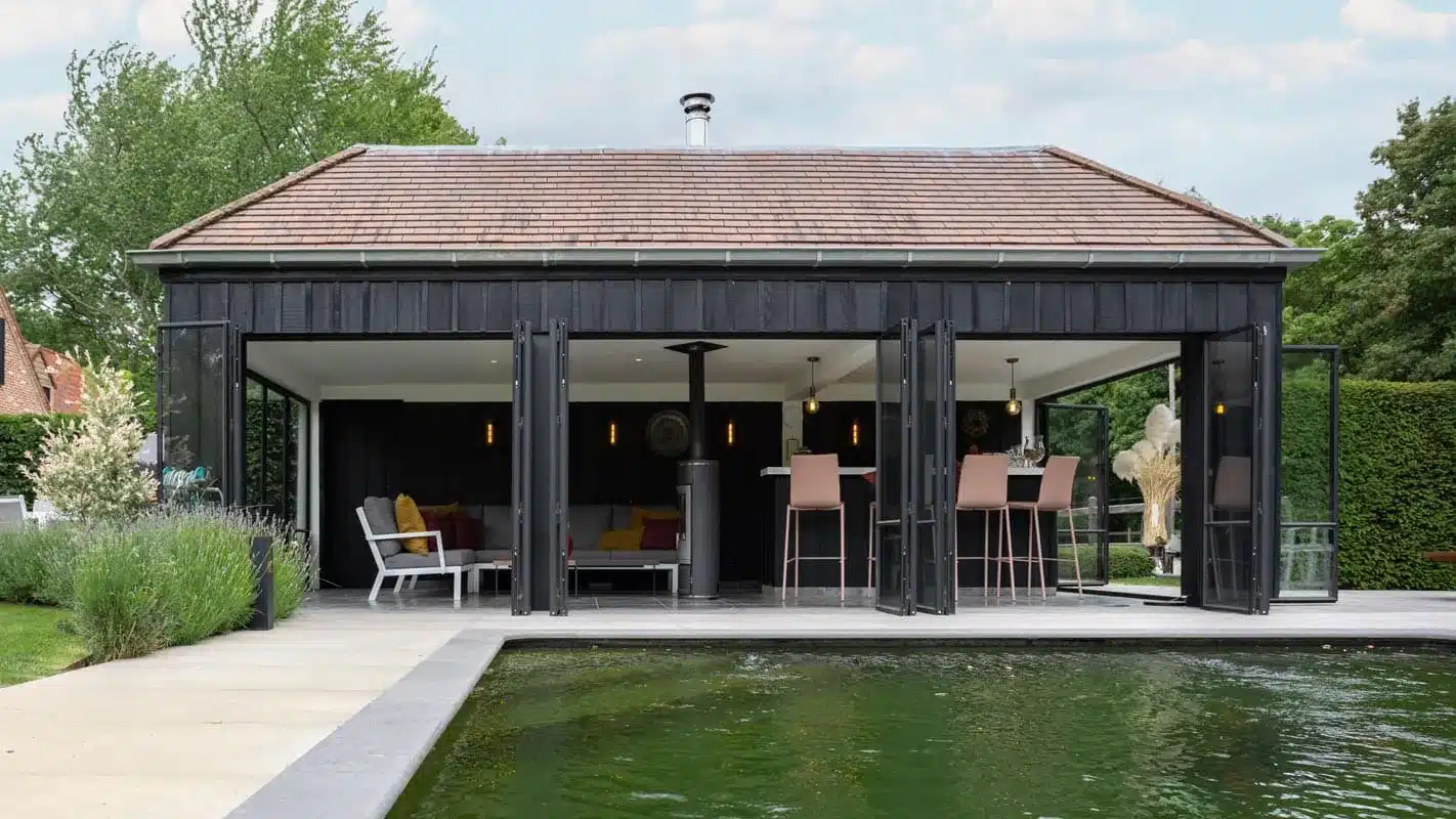 Poolhouse met volledig opengevouwen stalen harmonicadeuren, waardoor binnen en buiten één geheel vormen.