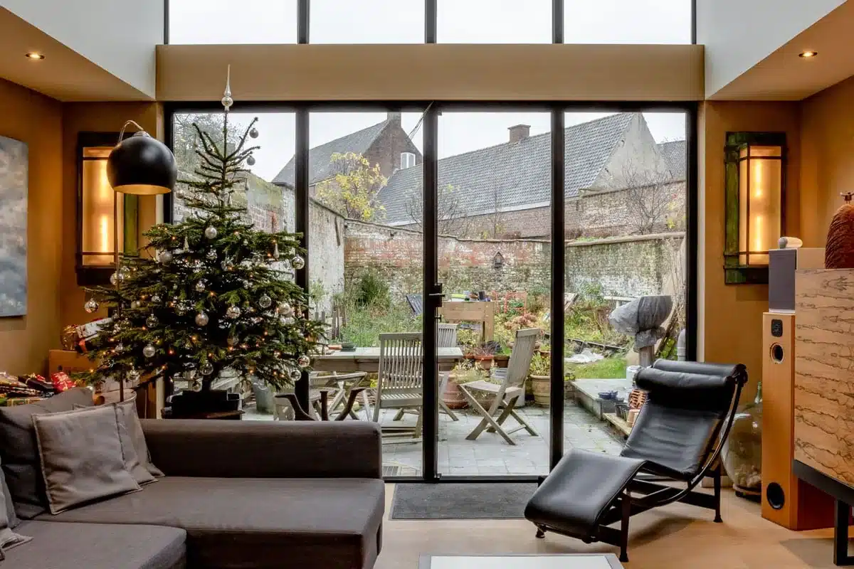Leefruimte van een gerenoveerde woning met een volledig stalen achtergevel met accordeondeuren naar de tuin.