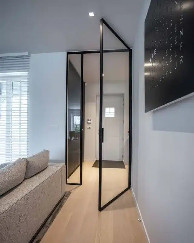 Geopende stalen binnendeur met vast zijlicht tussen leefruimte en hal van een villa, zonder roeden.