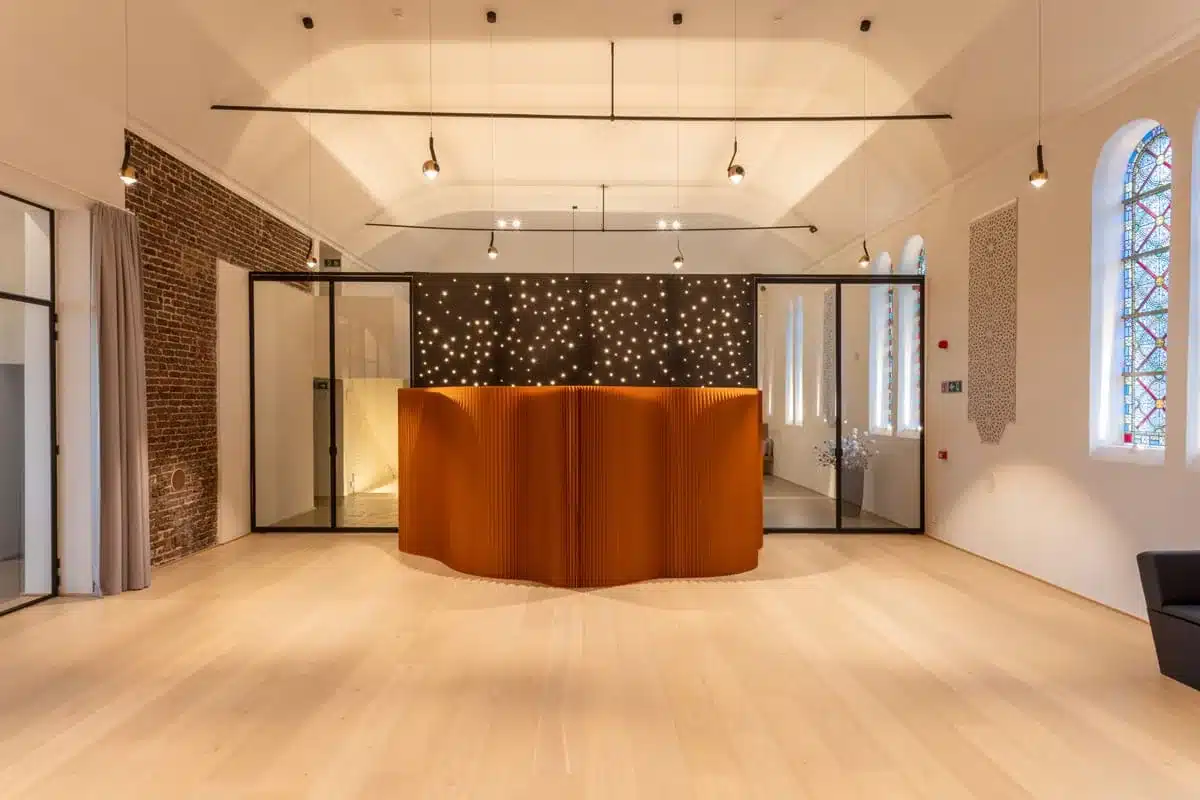 Inkomhal van een wellnesshotel met stalen glaswanden rond een zwarte sterrenwand en onthaal.