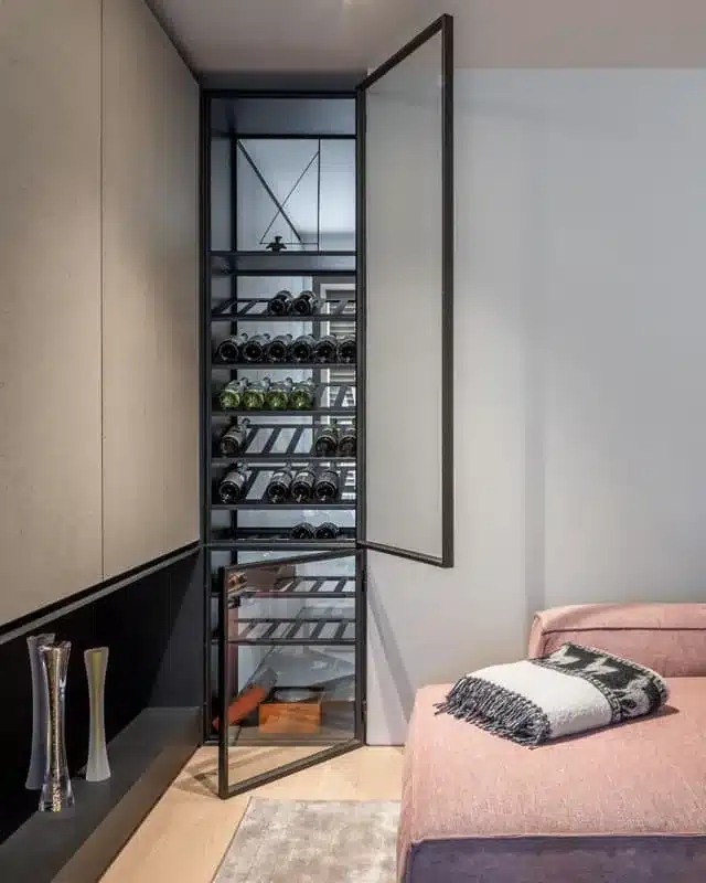 Stalen wijnkast met geopende glazen deur tussen living en vestiaire, met behoud van licht en doorzicht.