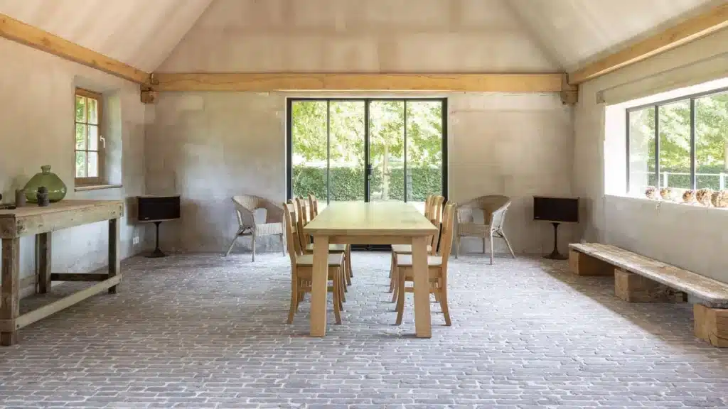 Interieur van een tuinpaviljoen met eiken spanten, een stalen deurpartij en stalen ramen naar de tuin.